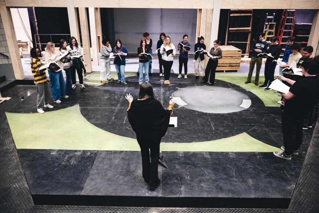 The choir rehearses on stage for a production of Into the Woods.
